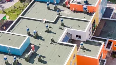 Aerial view of colorful apartment buildings with green roofs and chimneys in a residential area. 