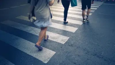 People crossing a city street at a pedestrian crossing, highlighting urban life and movement. 