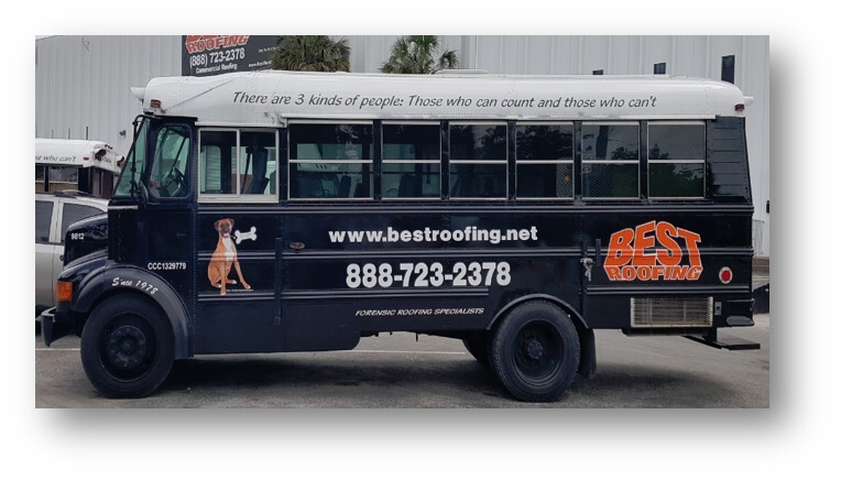 Black school bus with advertising for Best Roofing parked outside a building.