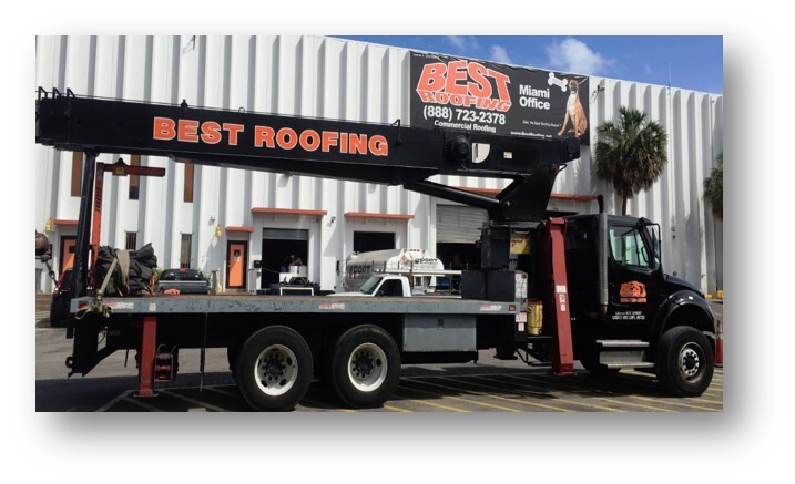 Black crane truck with advertising for Best Roofing parked outside a building.