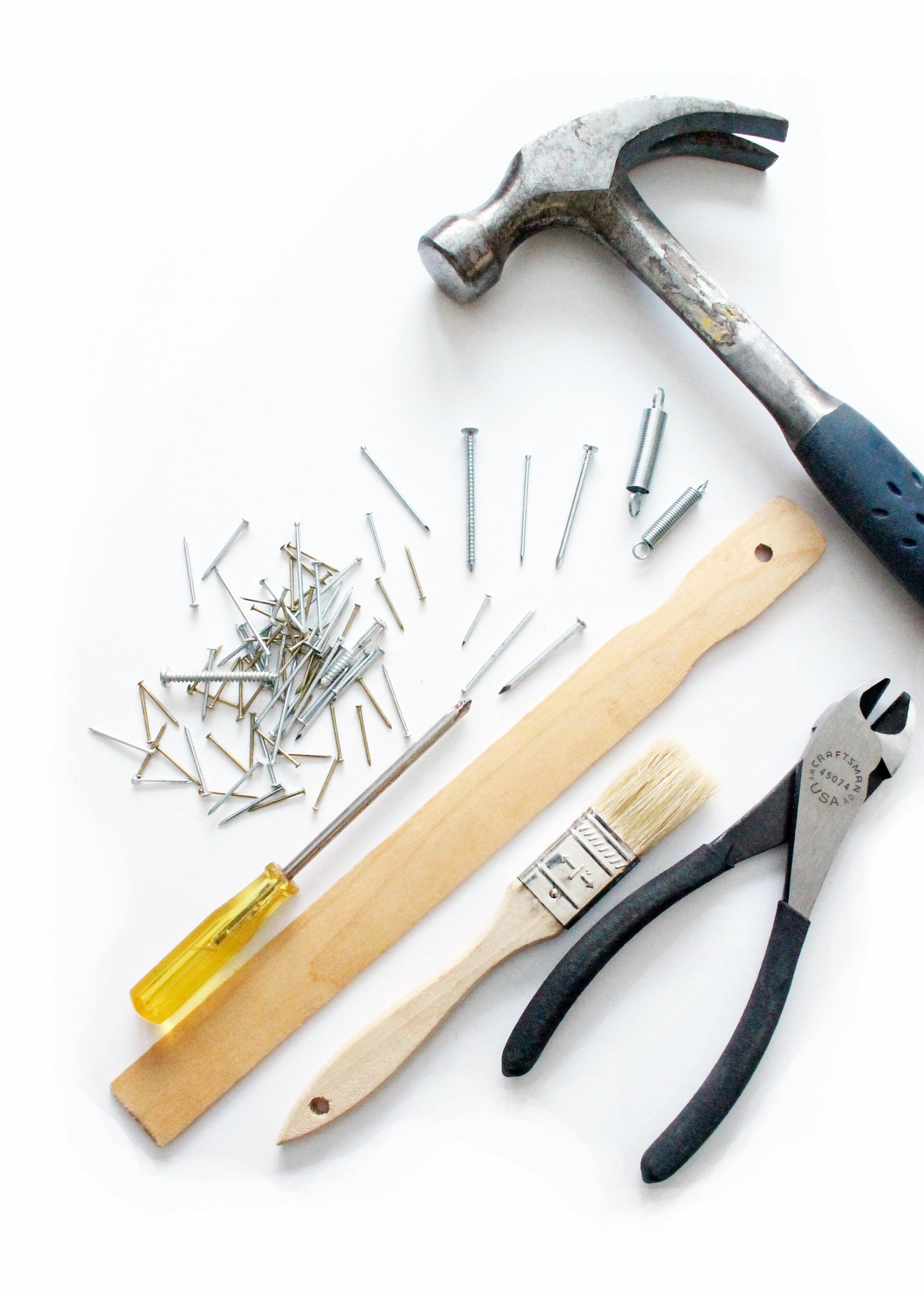 A collection of essential tools including a hammer, screws, screwdriver, and pliers on a white background.