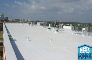 View of a flat white roofing system with ventilation units against a blue sky and city skyline.